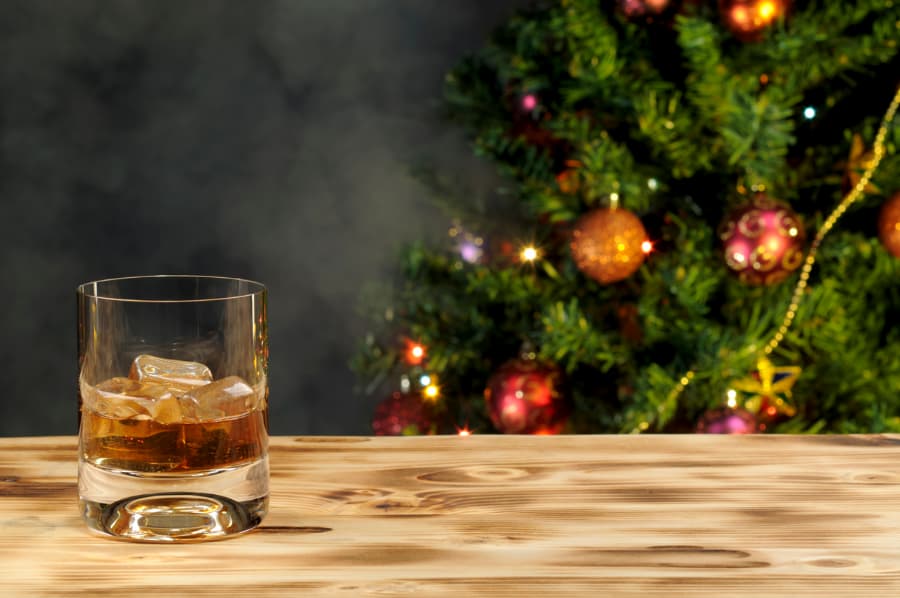 Glass of brandy on table next to Christmas tree